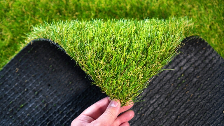 Hand folding down the corner of a piece of artificial grass